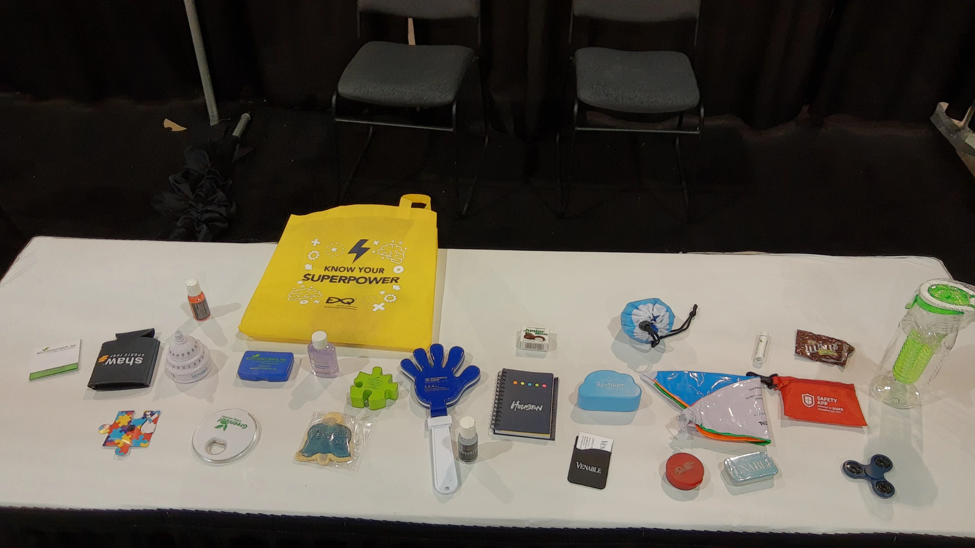 Table covered with branded trade show giveaways including pens, notepads and promotional items at an exhibition booth, illustrating why swag strategies often fail to generate qualified leads.