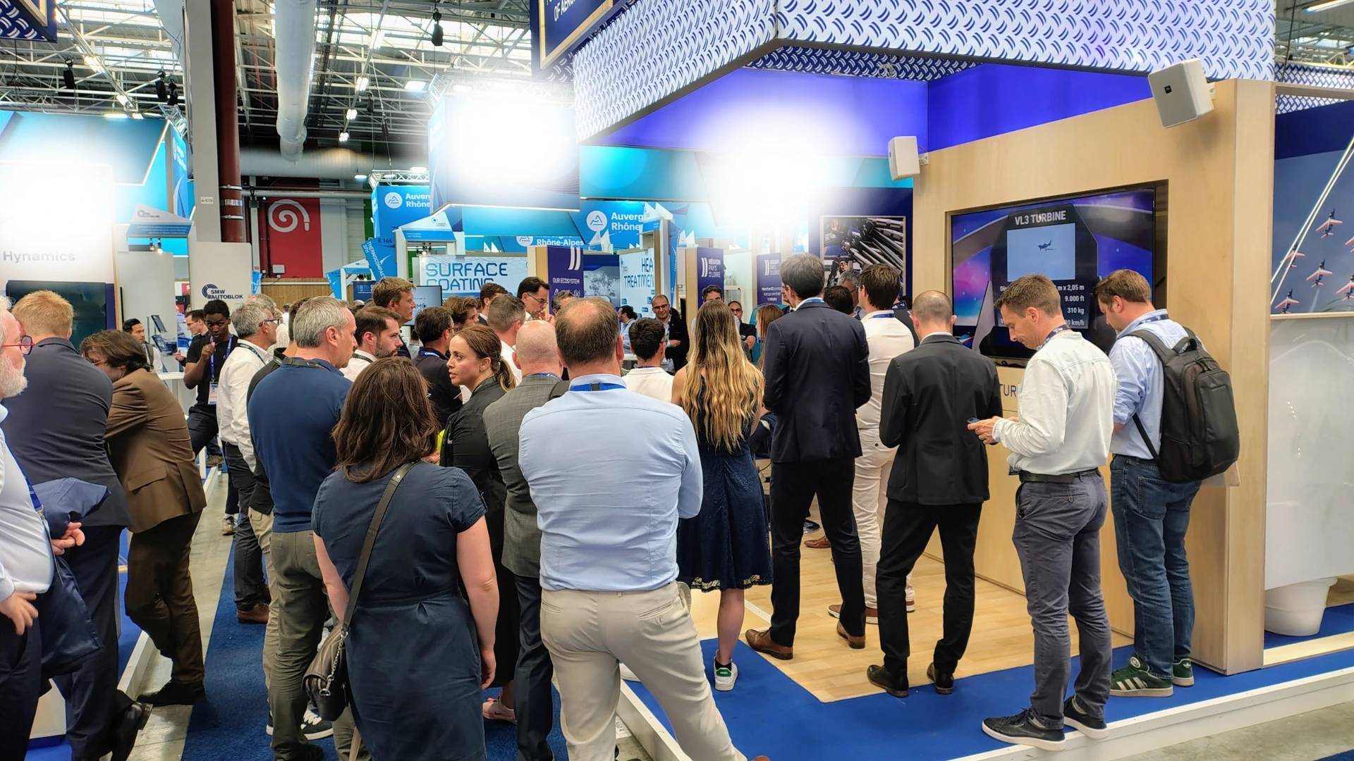 A crowded trade show booth floor with exhibitors and visitors engaging in conversations, representing active booth management and team execution during a live event.