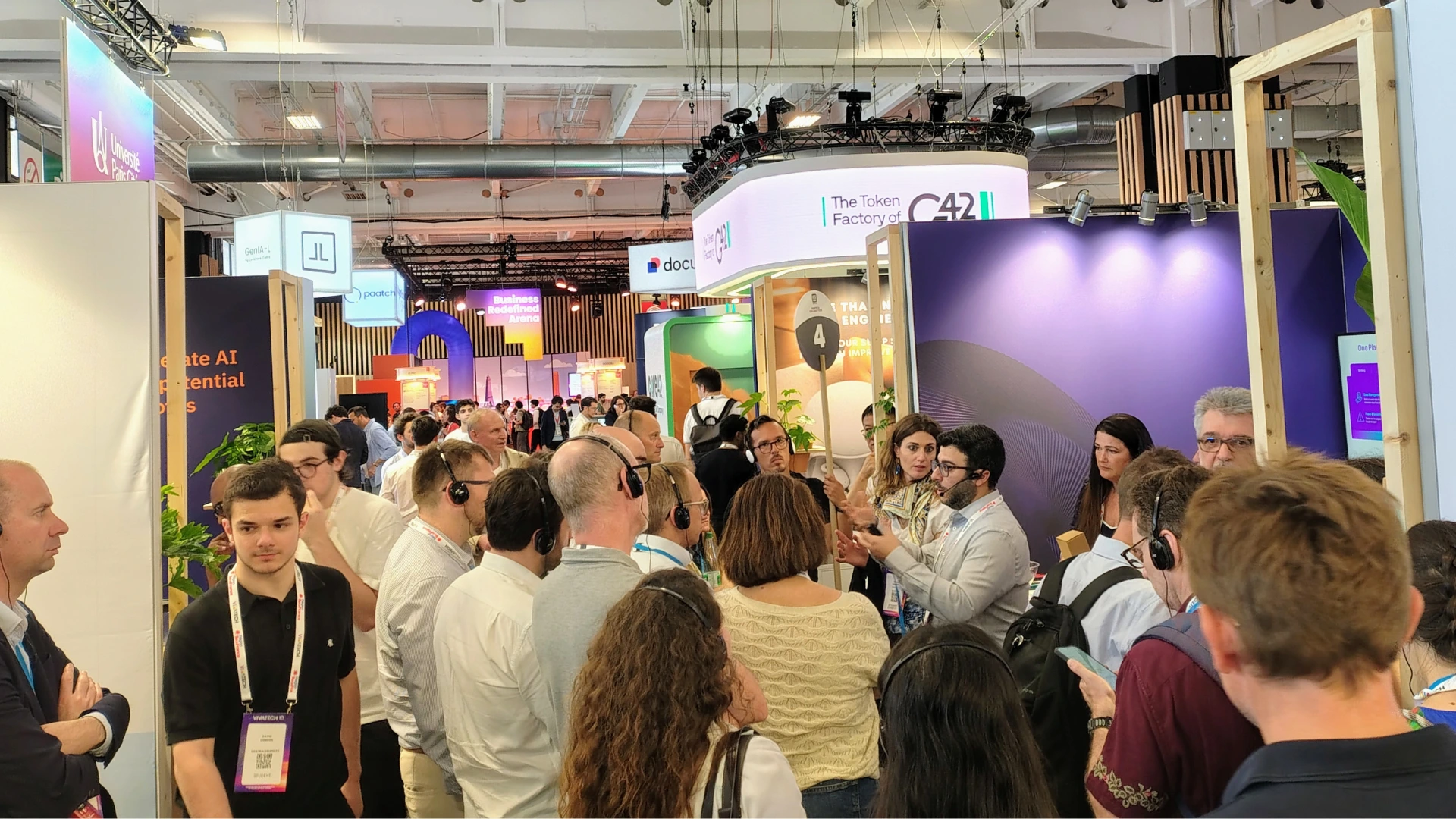 Trade show exhibitor presenting to engaged audience wearing headsets at convention booth demonstrating real results from exhibiting strategy